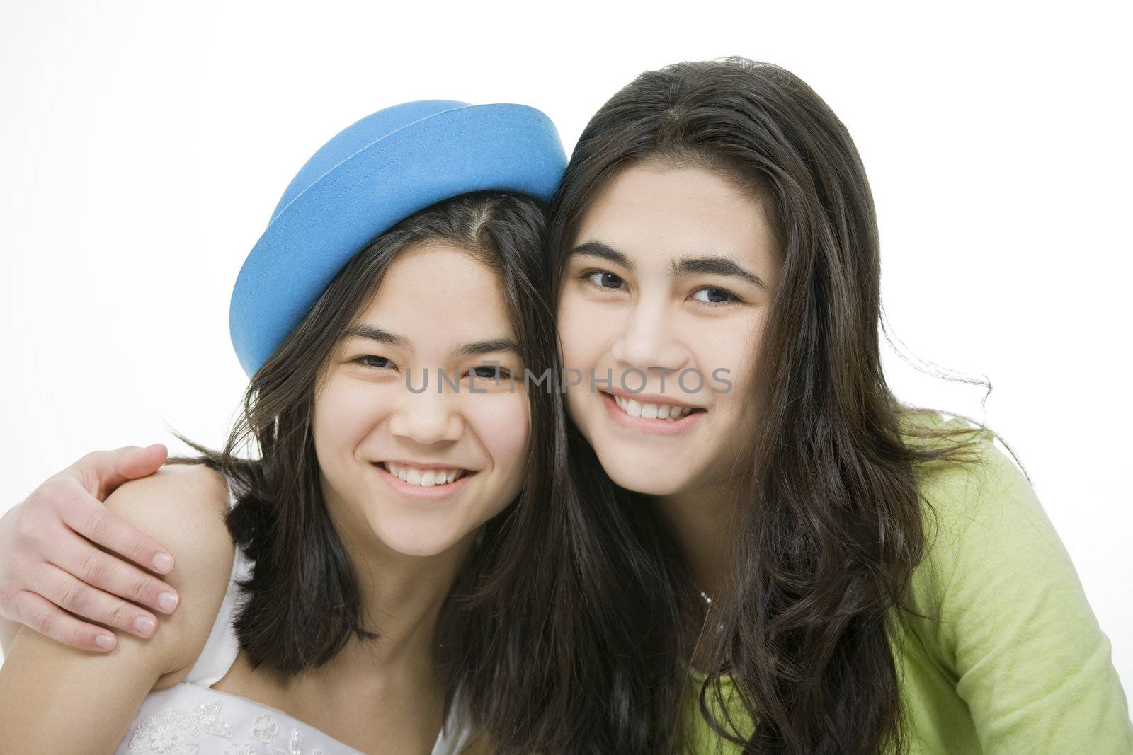 Two teen girls smiling together, hugging.