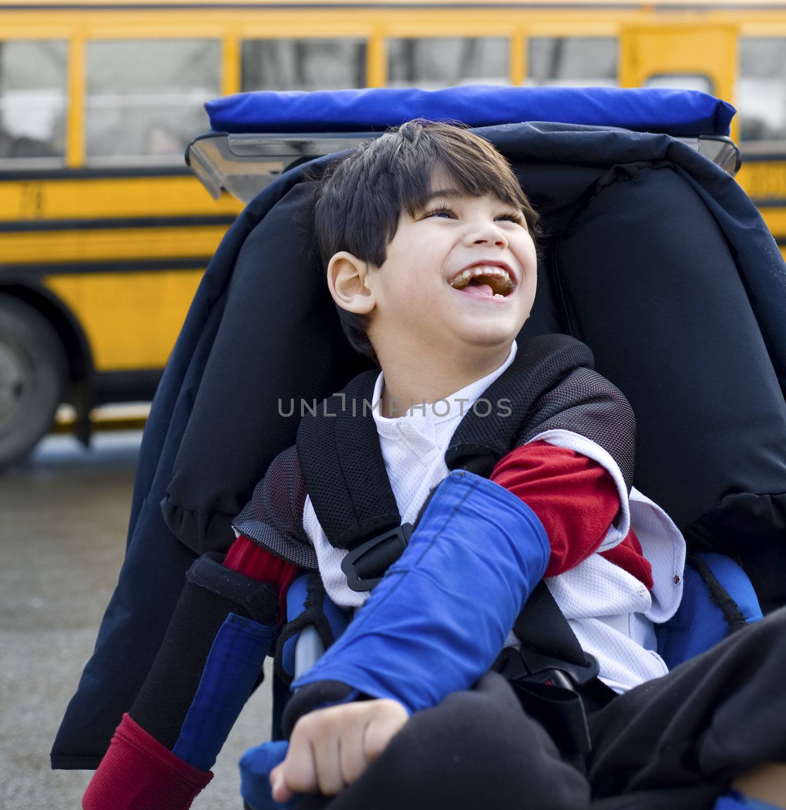 Disabled five year old boy in wheelchair, by schoolbus by jarenwicklund