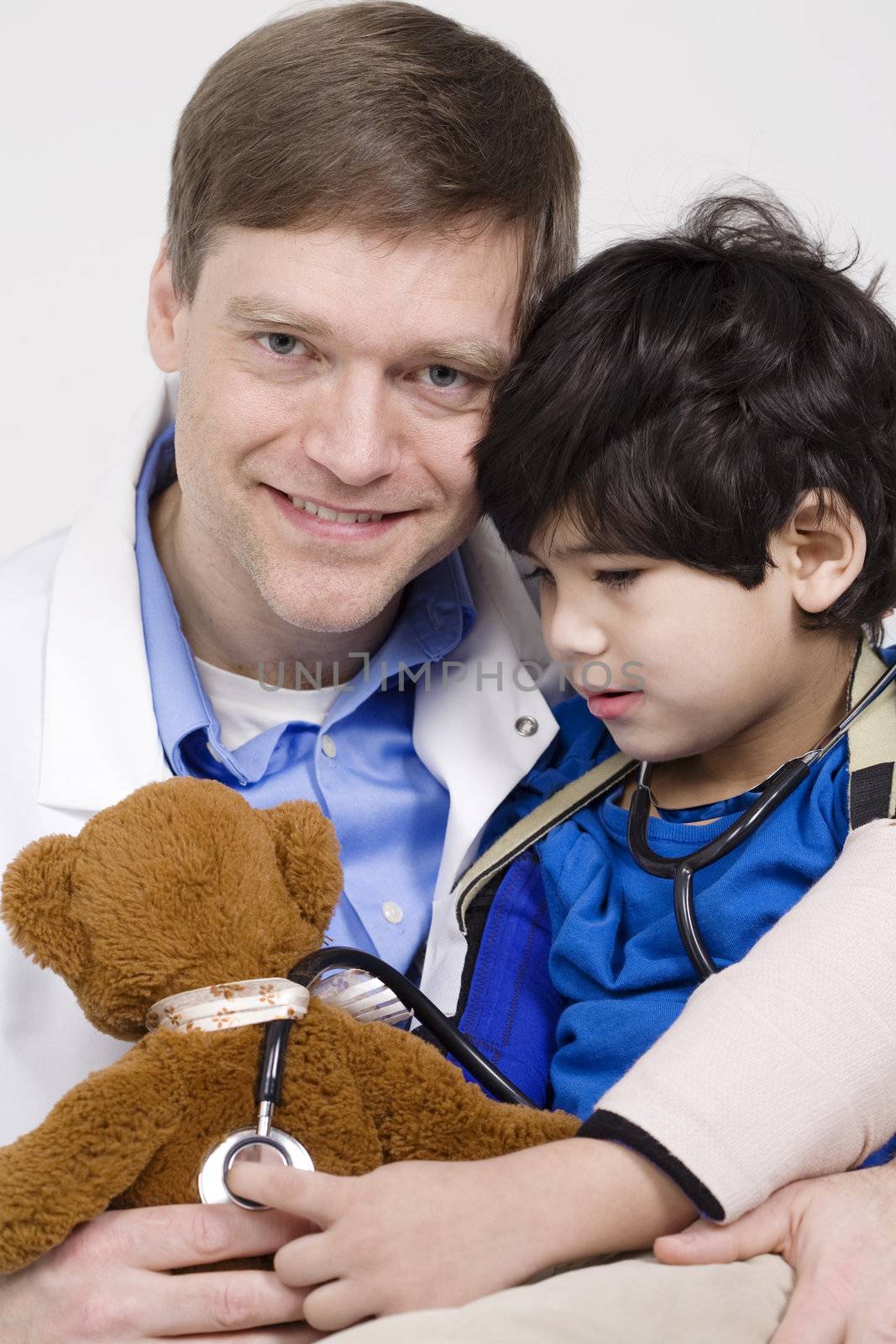 Friendly doctor playing with five year old disabled patient during office visit by playing with teddy bear doll together