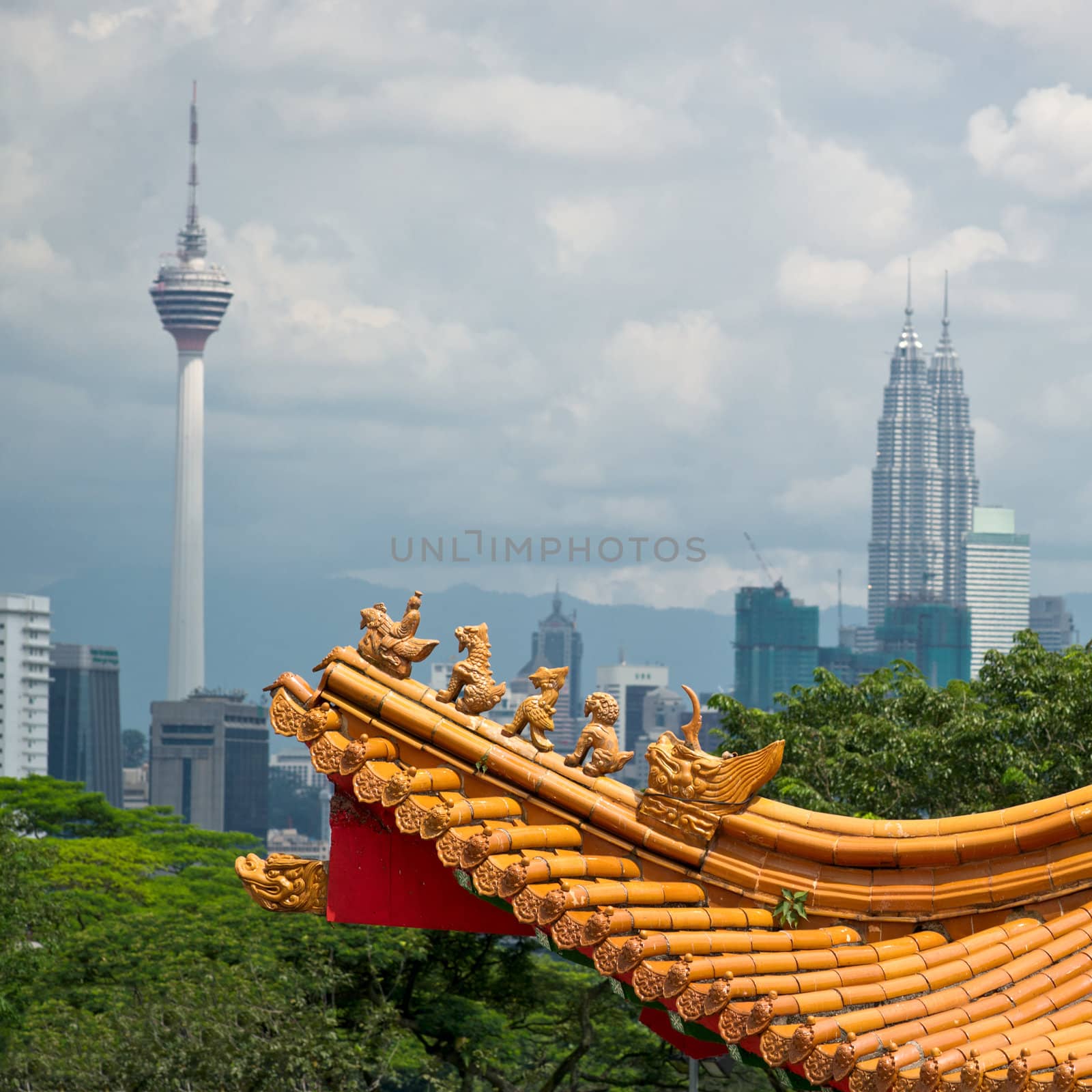Mixture of architectural styles in Kuala Lumpur, Malaysia.  The roof of ancient chinese temple on the background of two symbols of Kuala Lumpur - KL Tower and Petronas Twin Towers.
