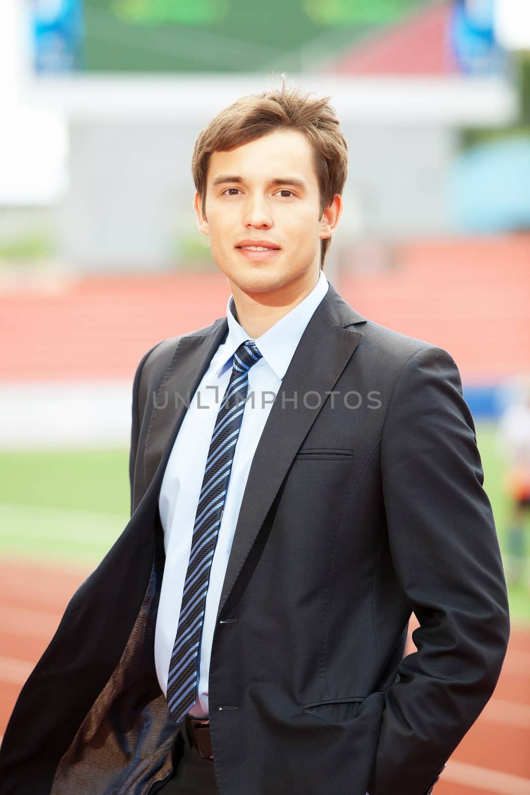 Satisfied smiling businessman standing in the summer outdoors.