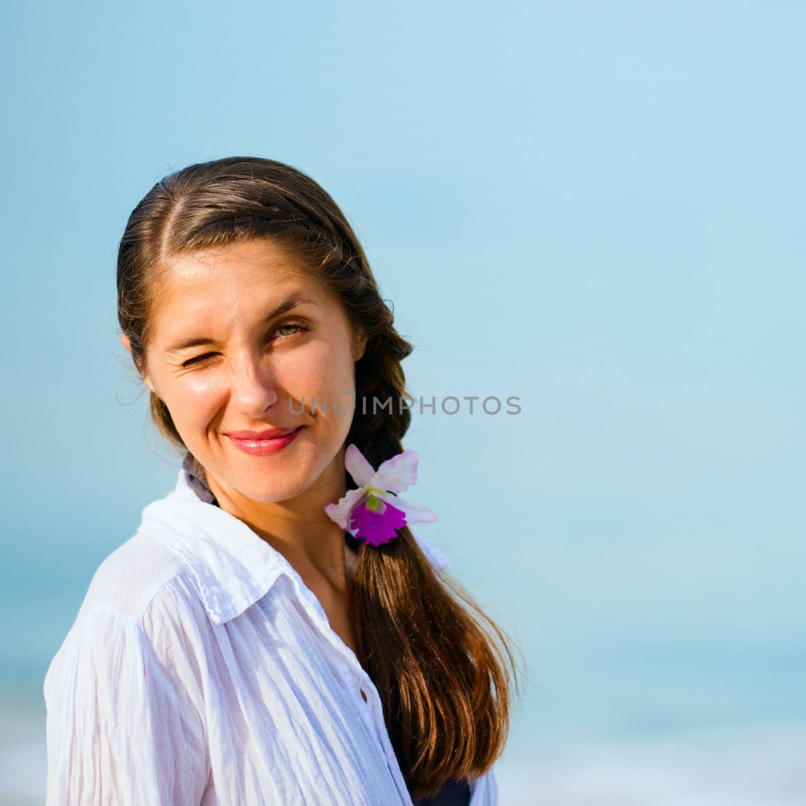 Portrait of young winking woman on the sky background