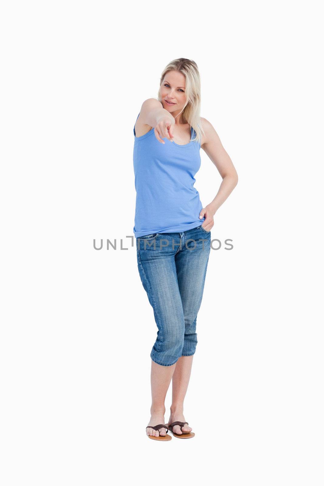 Relaxed blonde woman pointing her finger against a white background