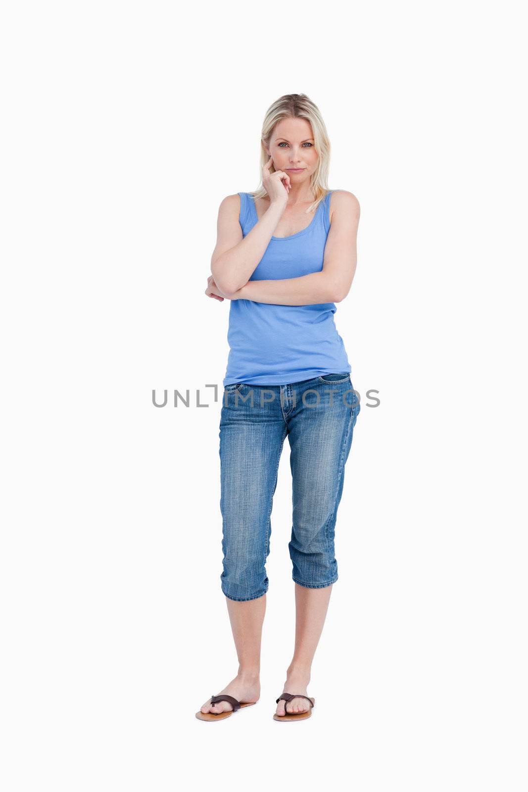 Blonde woman standing up with finger on her cheek against a white background