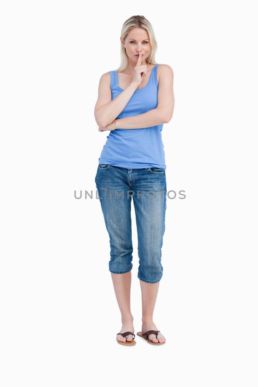 Blonde woman telling to be quiet while crossing arms against a white background