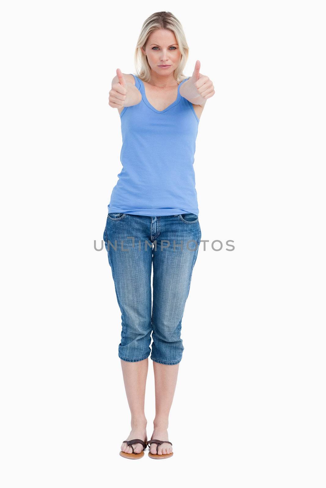 Serious blonde woman showing her thumbs up against a white background