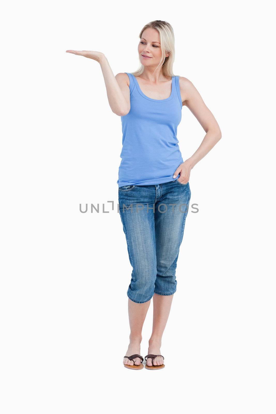 Blonde woman looking at her right hand palm up against a white background
