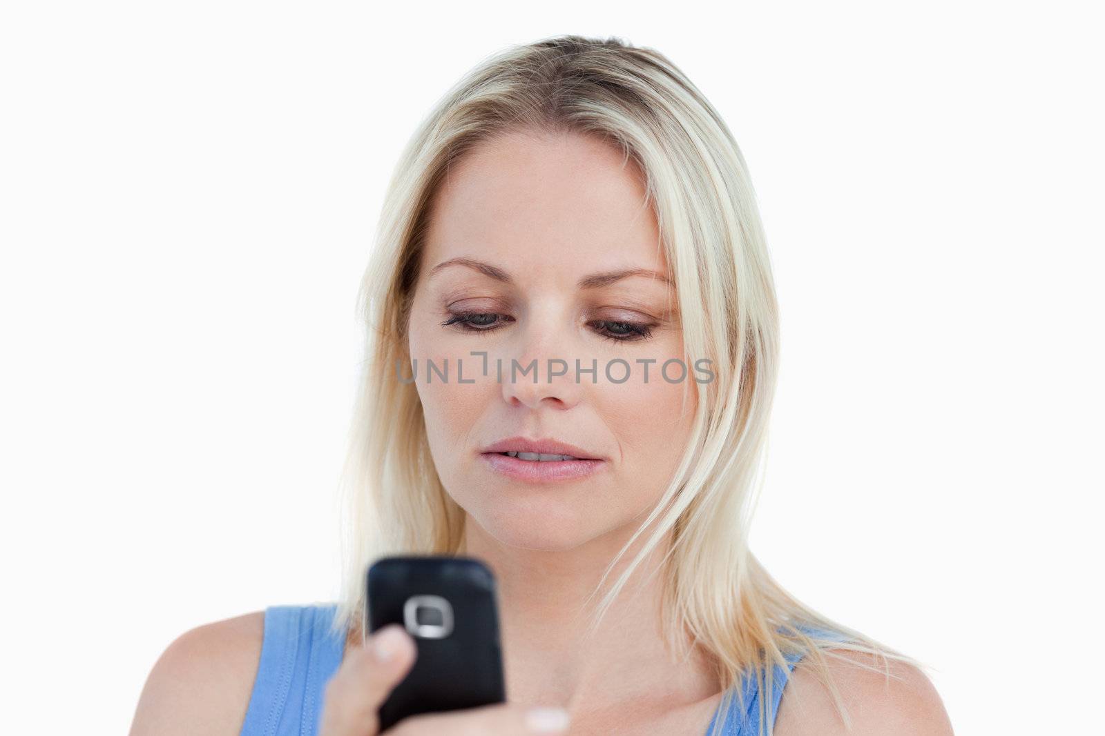 Serious blonde woman holding her cellphone against a white background