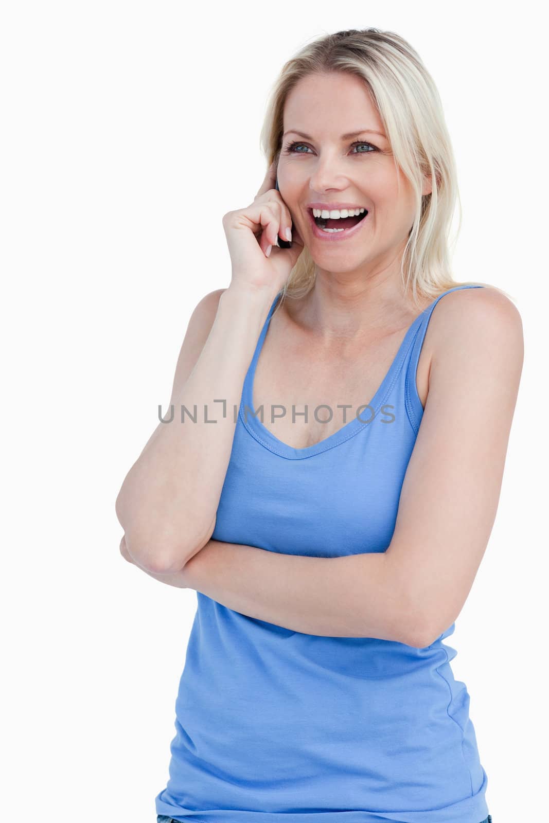 Blonde woman using a cellphone while laughing against a white background