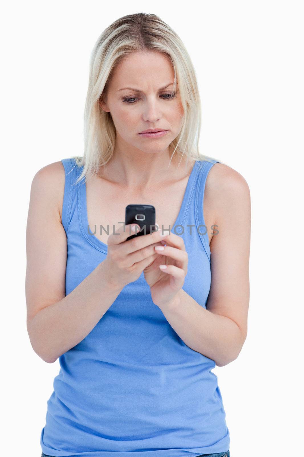 Serious blonde woman looking at her mobile phone against a white background