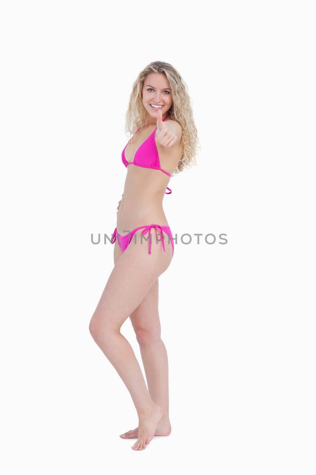 Side view of an attractive woman placing her thumbs up against a white background