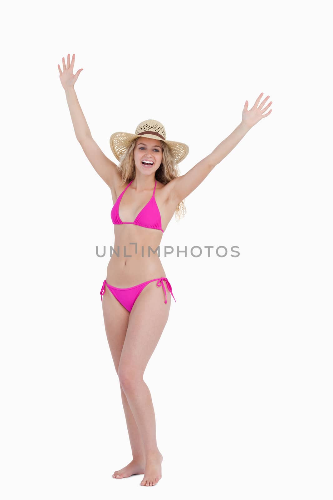 Blonde teenager raising her arms while standing upright against a white background