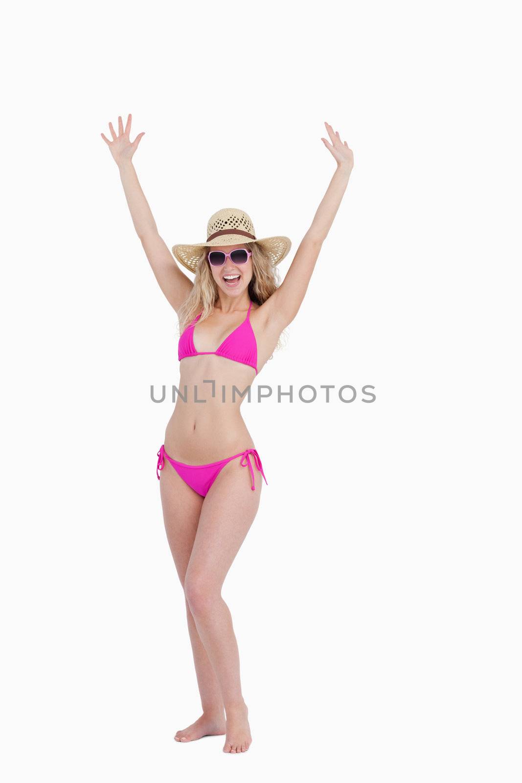 Teenager in a swimsuit raising her arms above the head against a white background