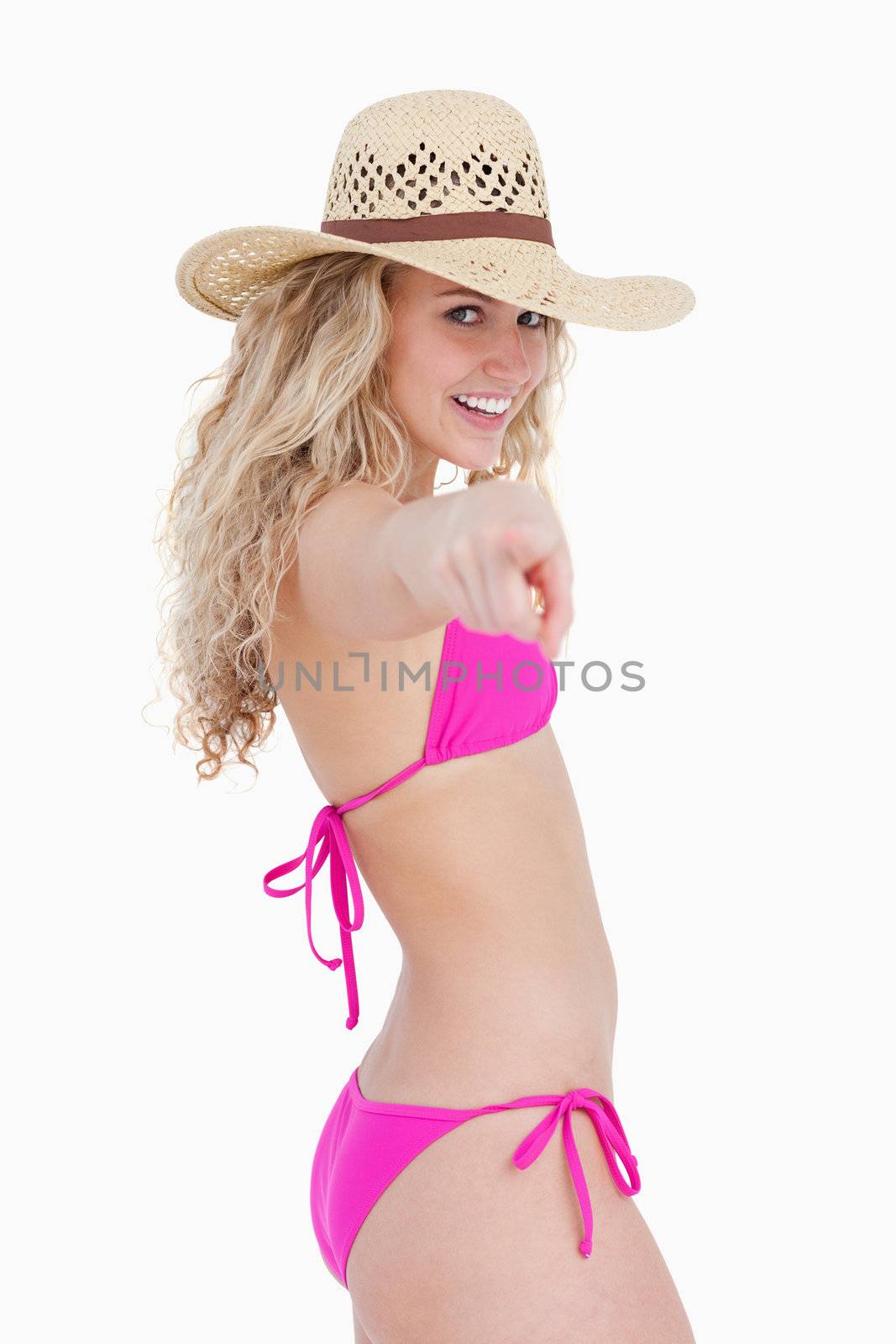 Smiling attractive teenager pointing her finger against a white background