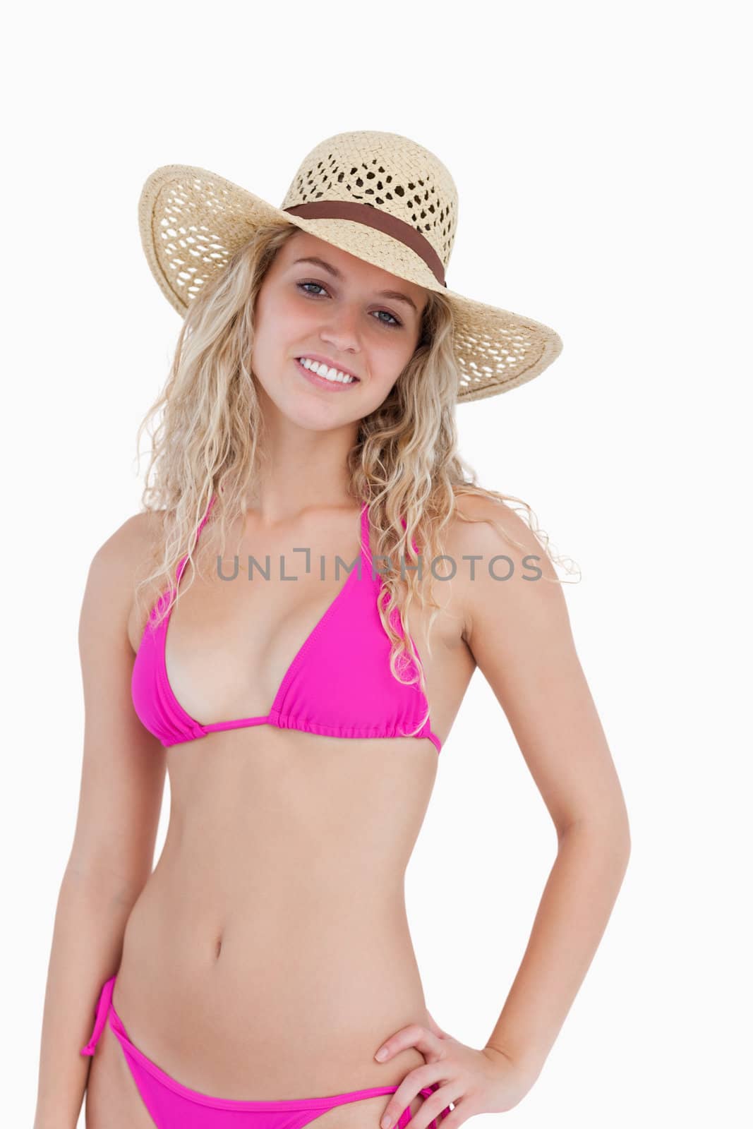 Smiling blonde teenager placing her left hand on her hip against a white background