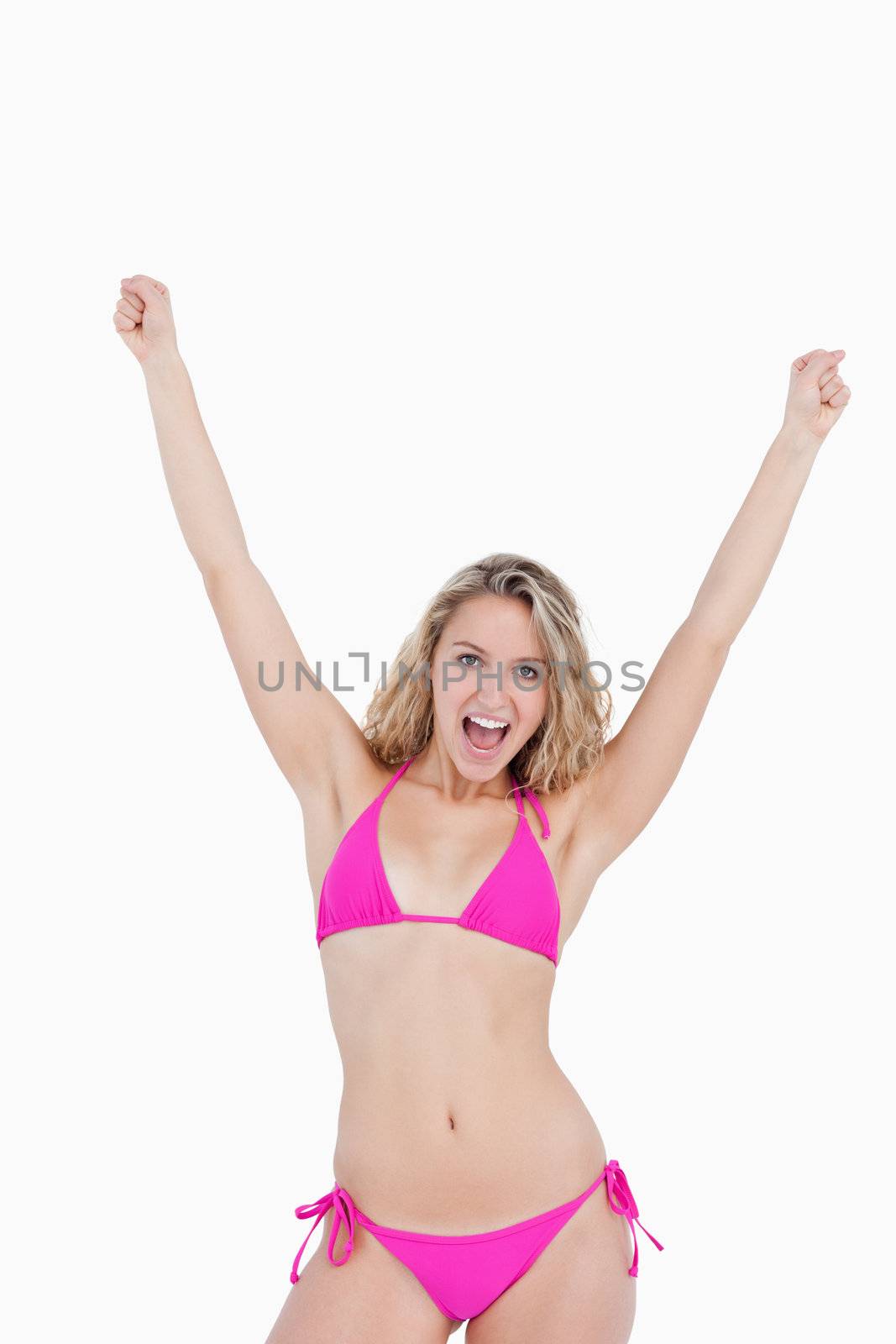 Young attractive woman in beachwear raising her arms against a white background