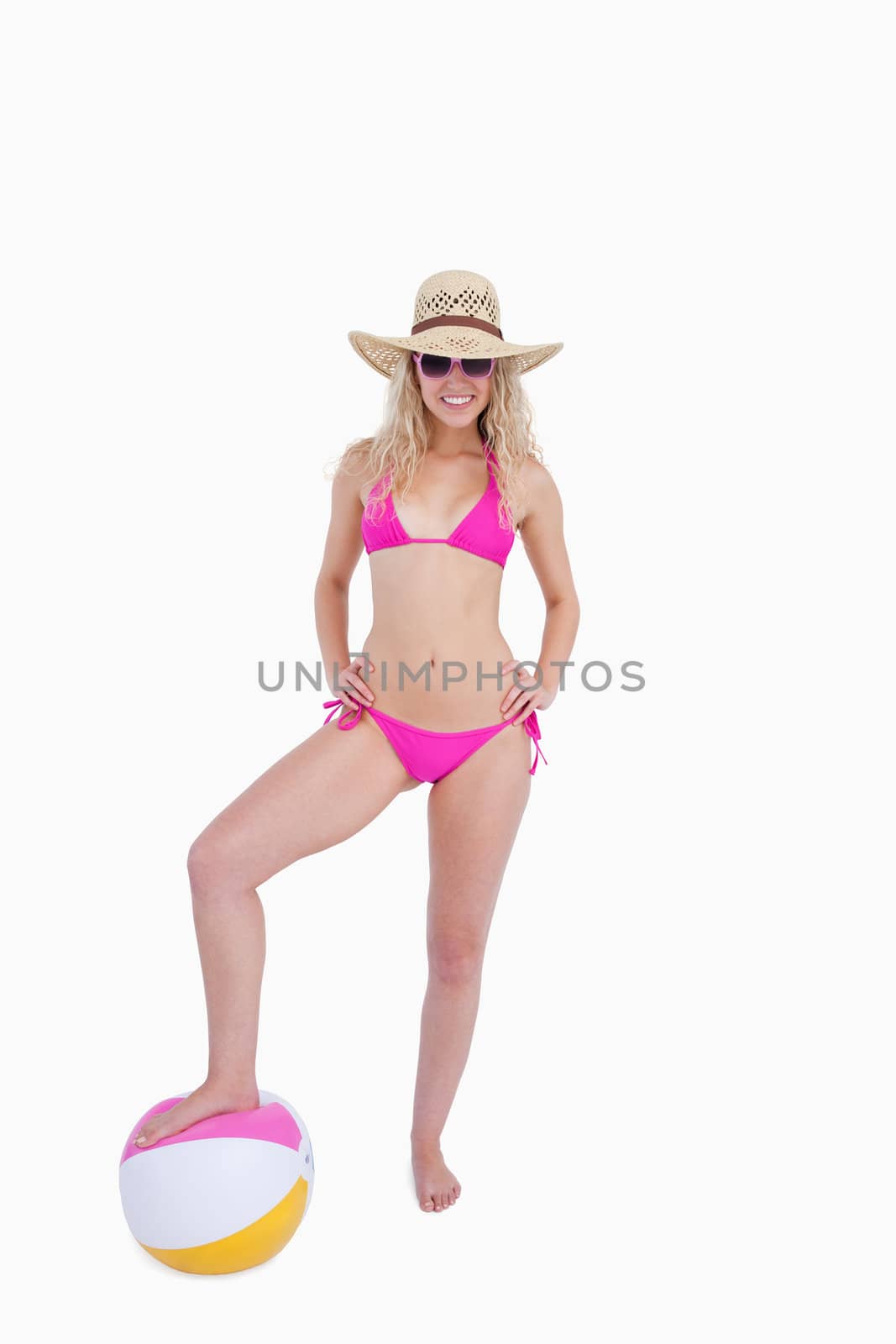 Attractive young woman putting her hands on her hips while placing foot on a beach ball