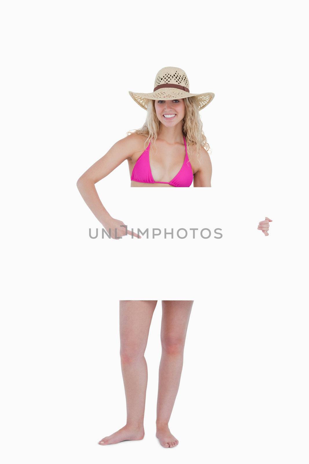 Smiling blonde woman pointing her finger at a blank poster by Wavebreakmedia