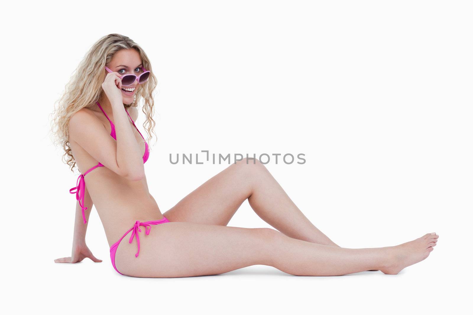 Attractive teenager sitting down while looking over her sunglass by Wavebreakmedia