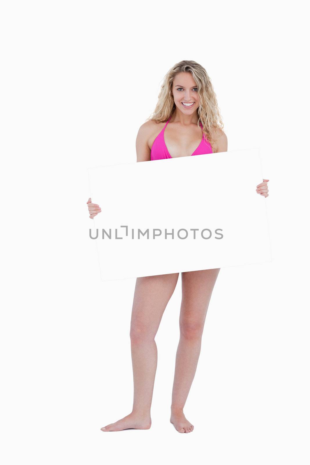 Smiling attractive teenager holding a blank poster while looking in front of her