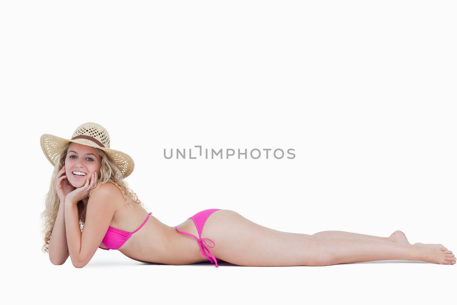 Smiling young woman lying down with her hands on her cheeks against a white background