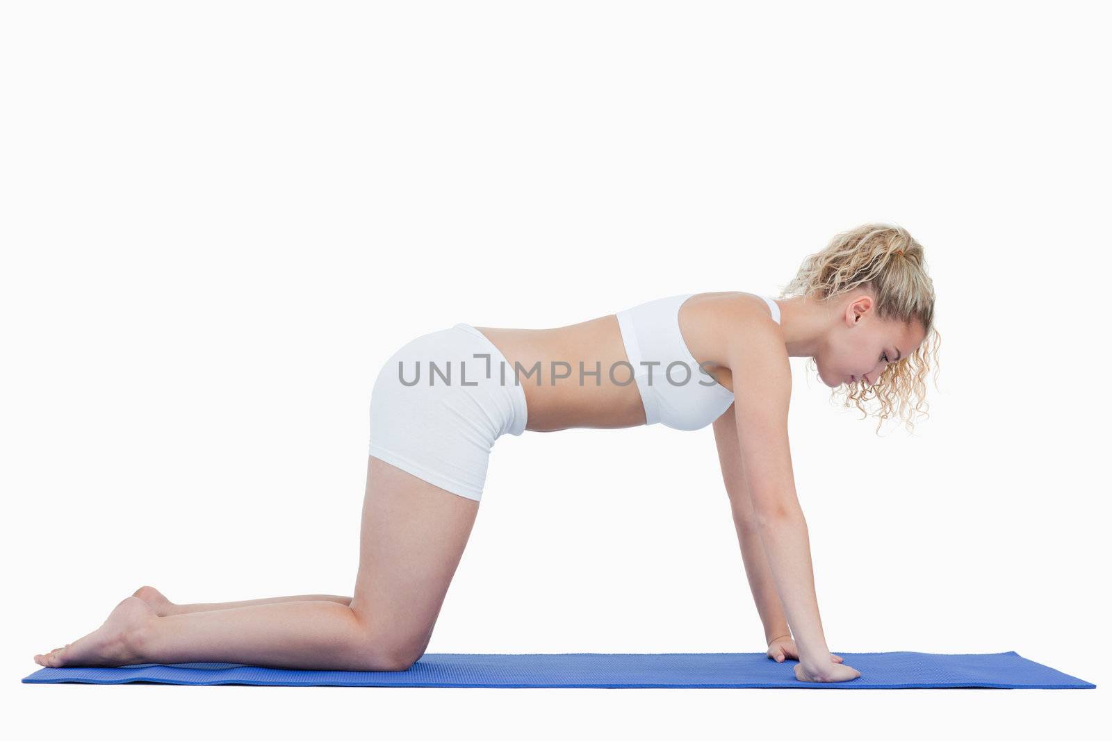 Blonde teenager doing gymnastics on all fours against a white backgrounds