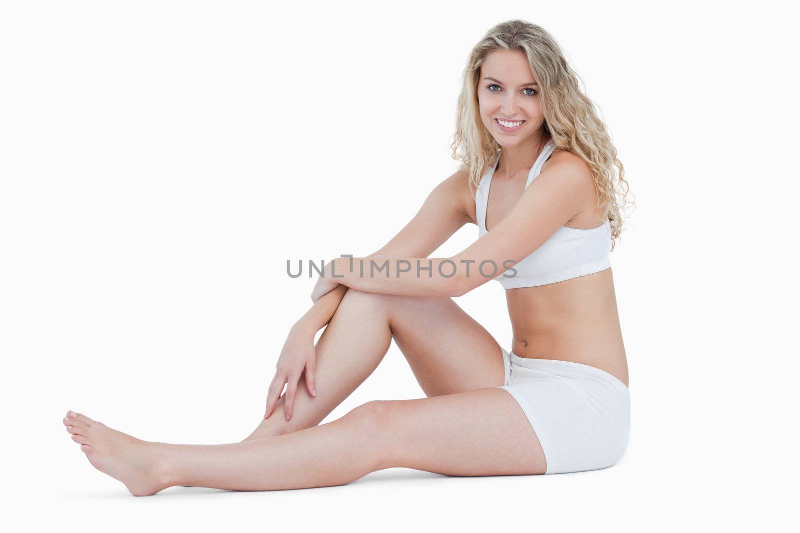 Smiling teenage sitting on the floor in underwear against a white background