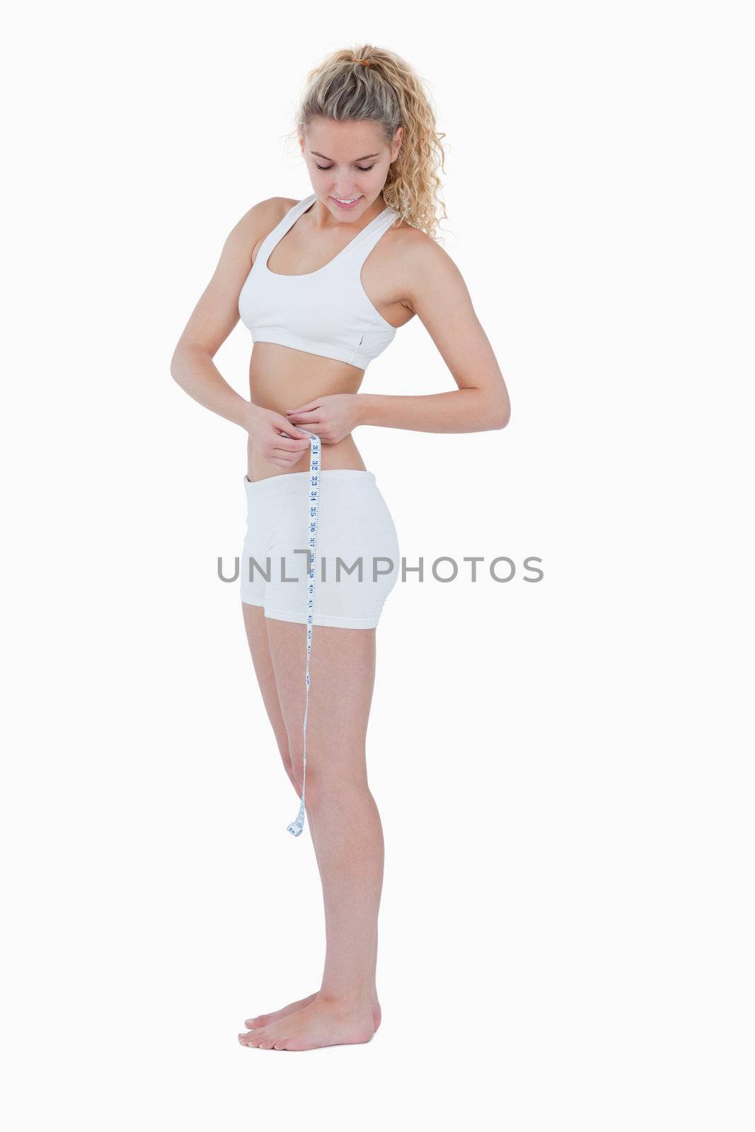 Young woman looking at her measuring tape against a white background