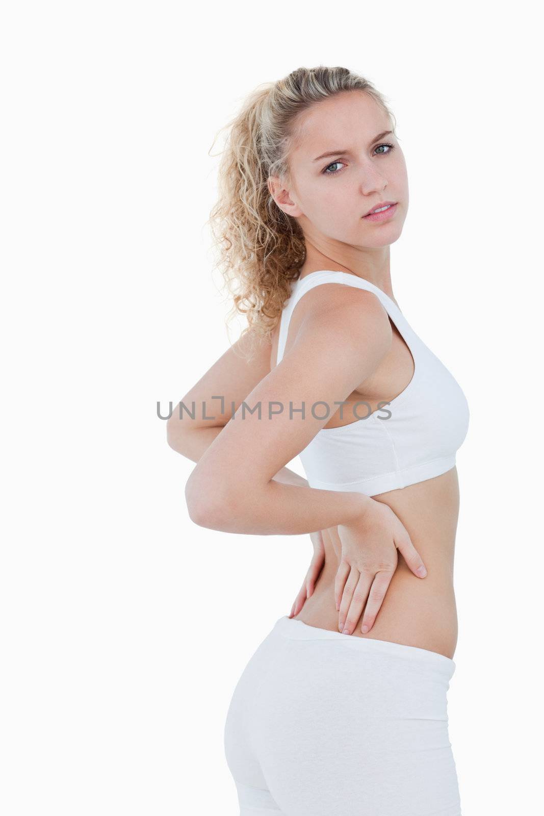 Young attractive woman touching her back against a white background