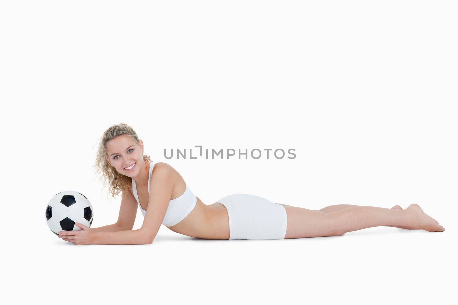 Young smiling woman lying down while holding a football by Wavebreakmedia