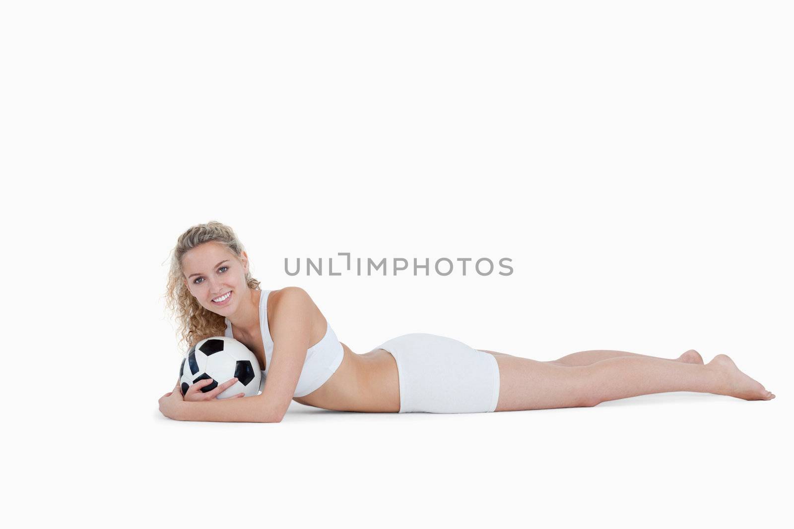 Smiling teenager holding a football close to her against a white background