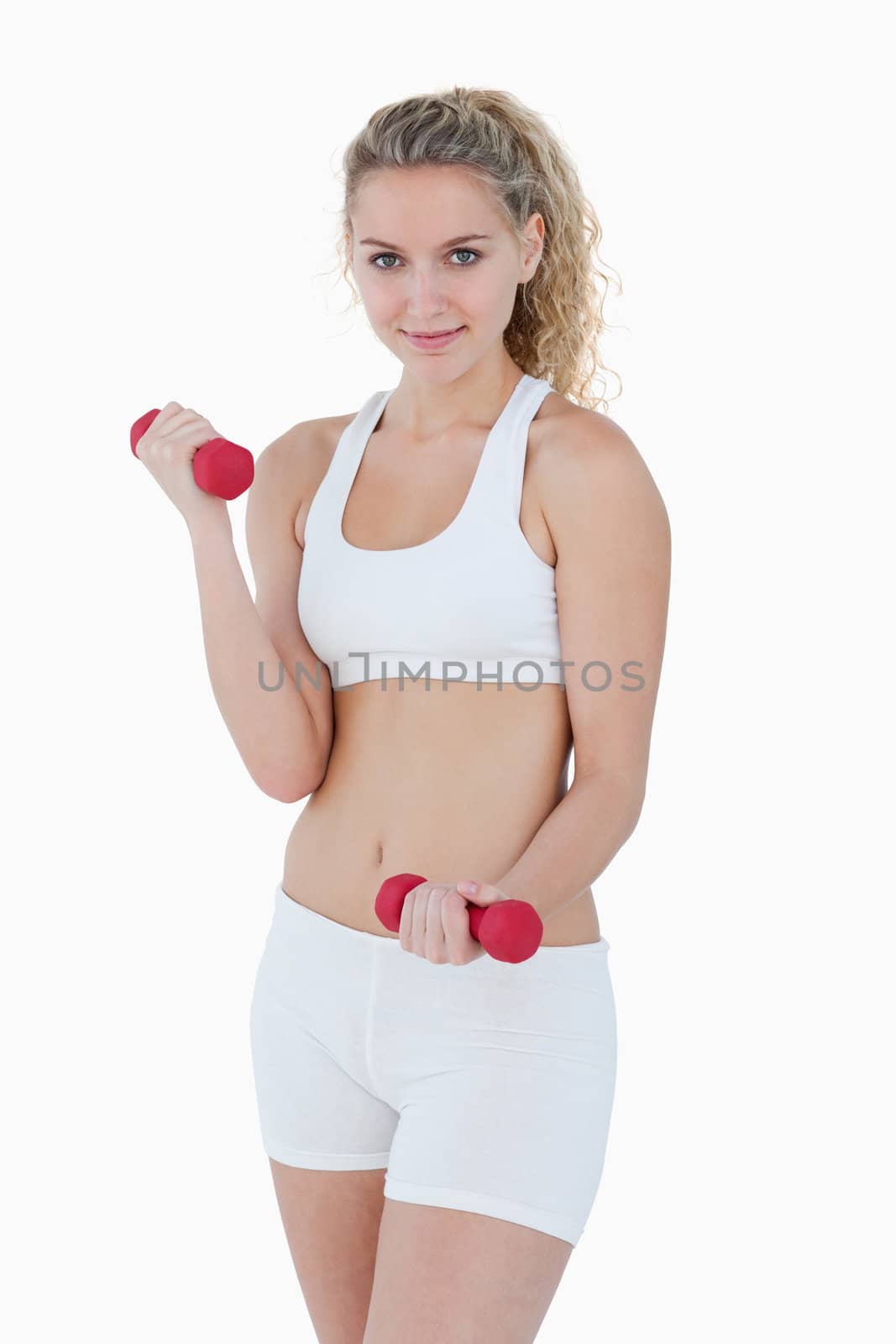 Young smiling woman lifting weights against a white background