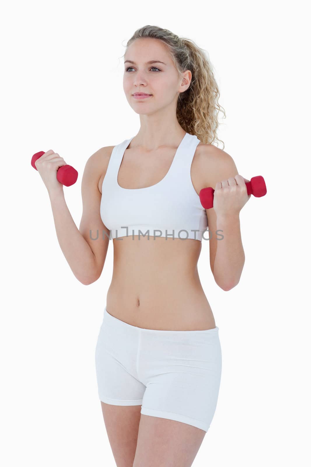 Concentrated teenager lifting red weights against a white background