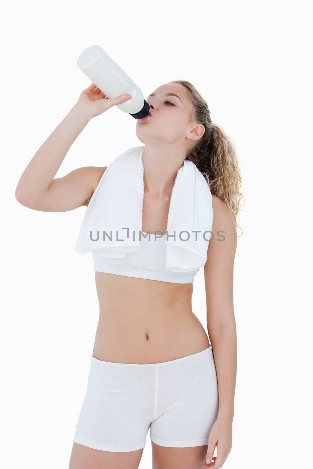 Young woman drinking water during sports against a white background