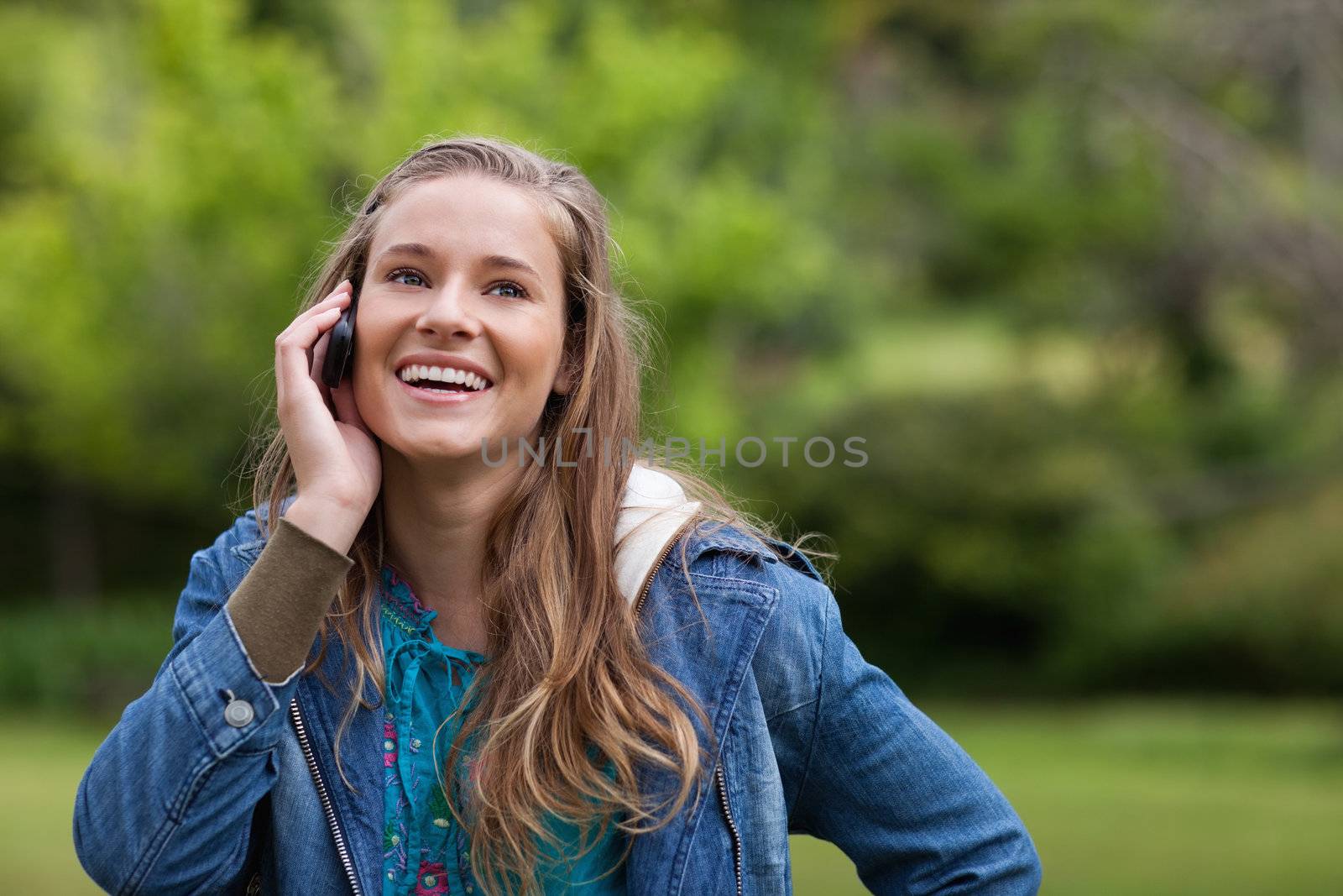 Teenage girl using her mobile phone while showing a great smile by Wavebreakmedia