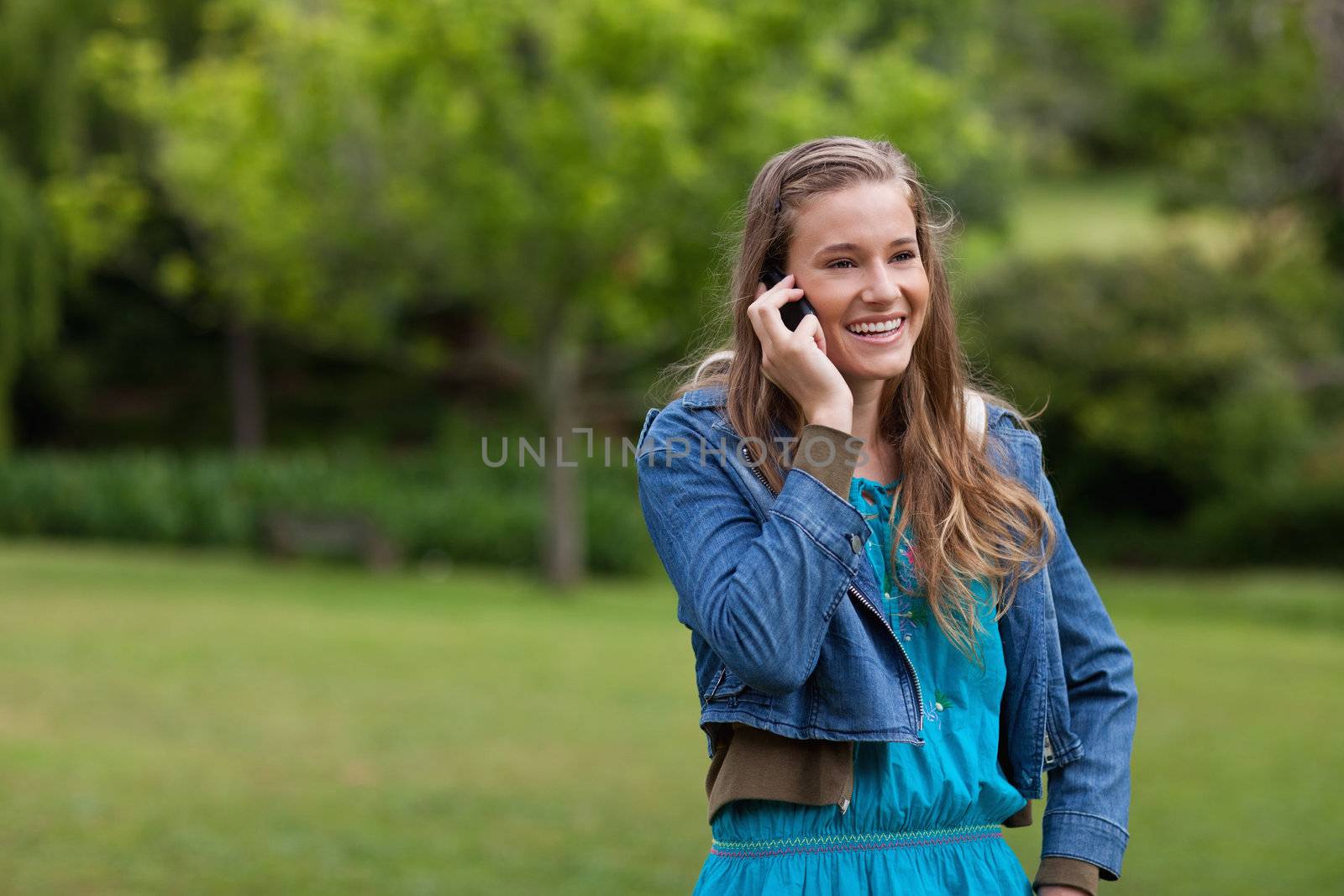 Teenage girl standing in the countryside while talking on the ph by Wavebreakmedia
