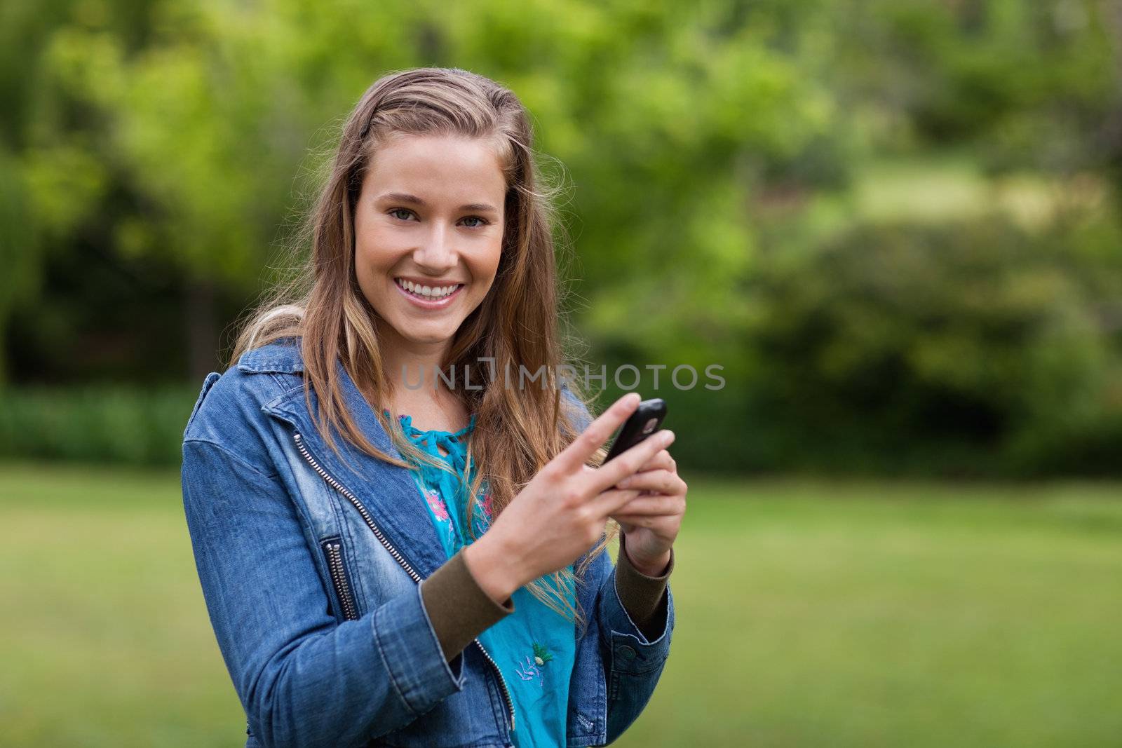 Smiling teenager sending a text with her cellphone