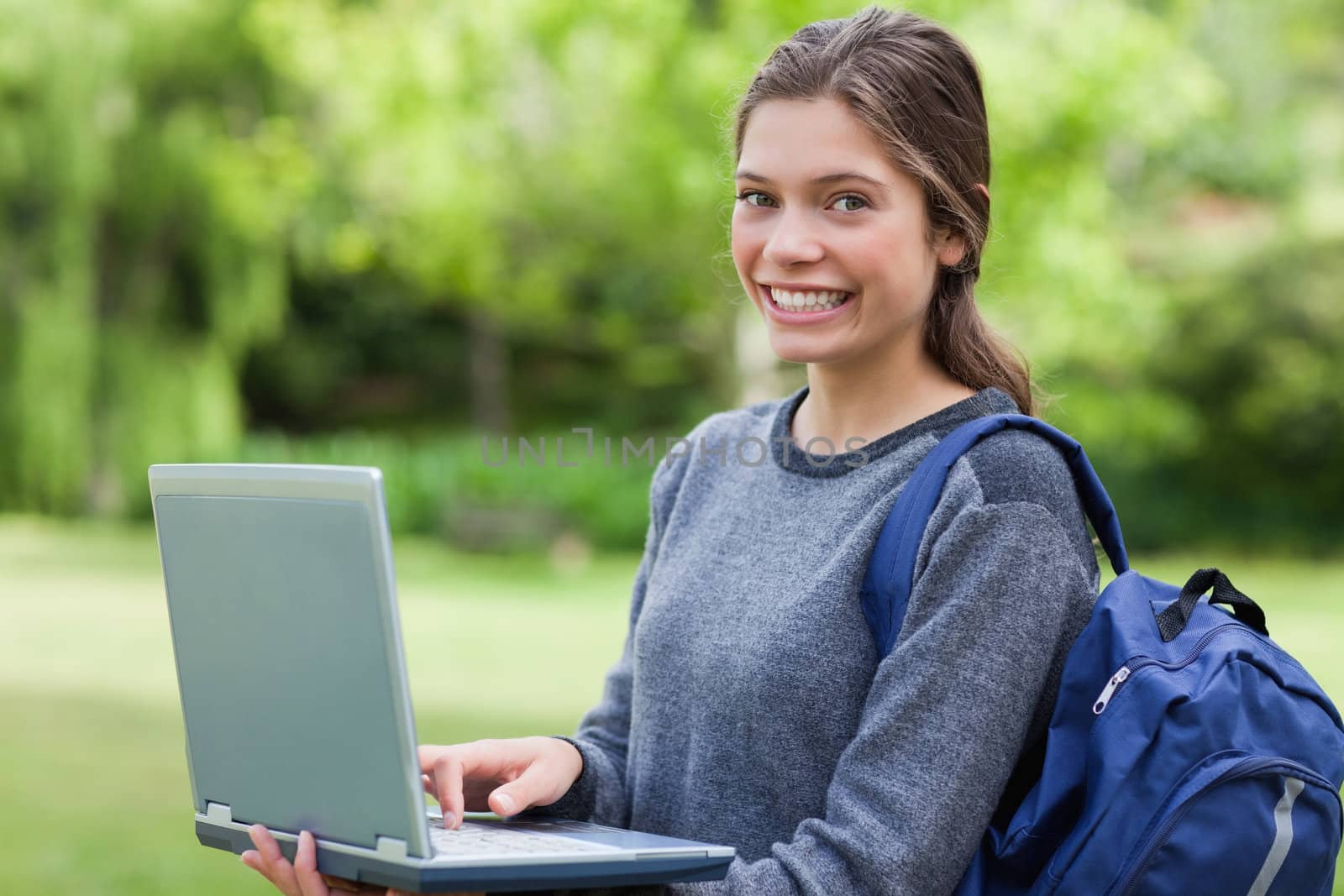Happy young girl holding her laptop while smiling in front of th by Wavebreakmedia