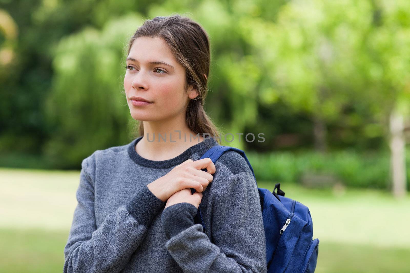 Young relaxed girl looking towards the side while standing upright in a park