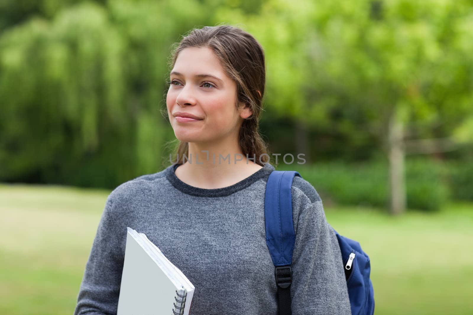 Young smiling woman looking far away while standing in a park wi by Wavebreakmedia