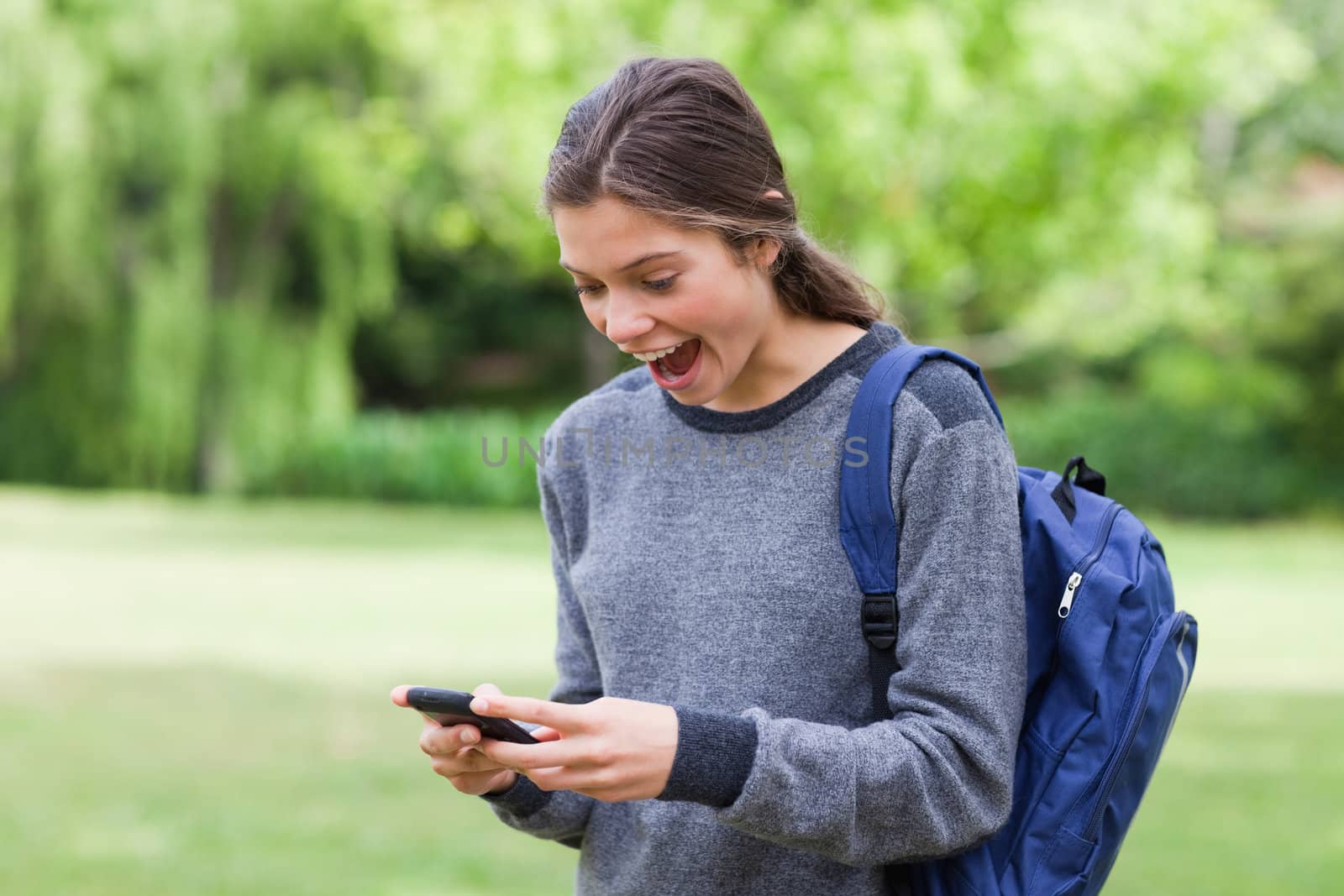 Young cute girl showing her surprise after receiving a text on her mobile phone