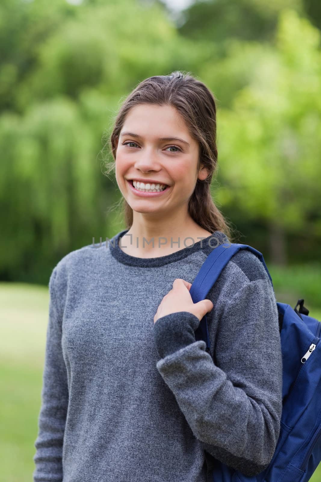 Young girl standing up with hair tied while carrying her backpac by Wavebreakmedia