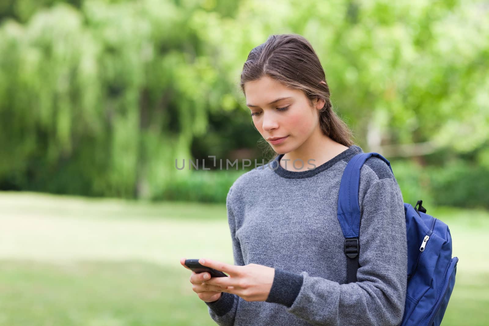 Young calm girl using her mobile phone to send a text by Wavebreakmedia