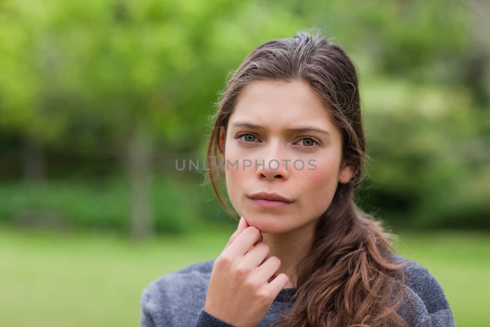 Thoughtful young girl placing her hand on chin while standing in by Wavebreakmedia