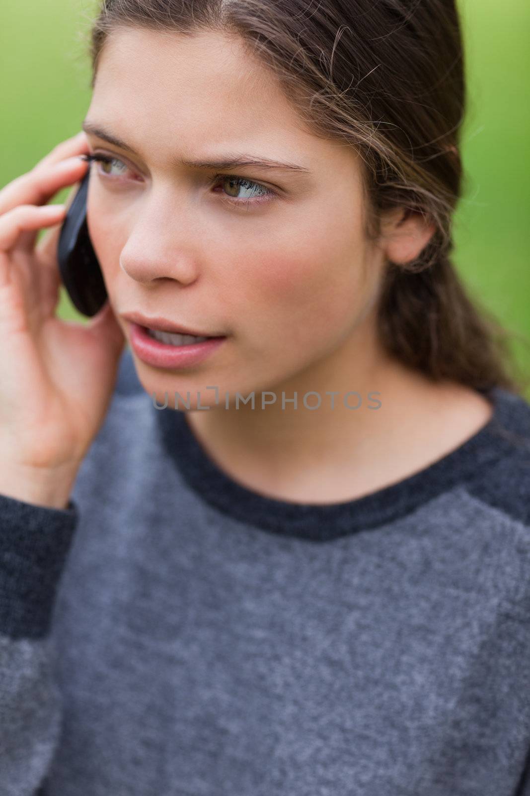Serious teenager talking with her mobile phone while looking towards the side