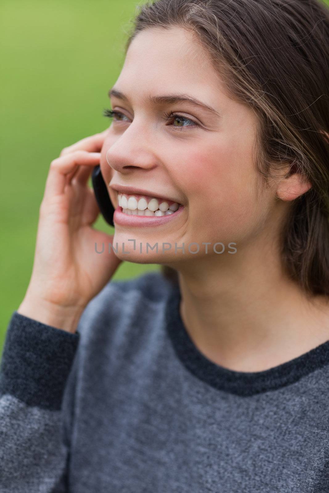 Young smiling girl calling with her cellphone while standing up by Wavebreakmedia