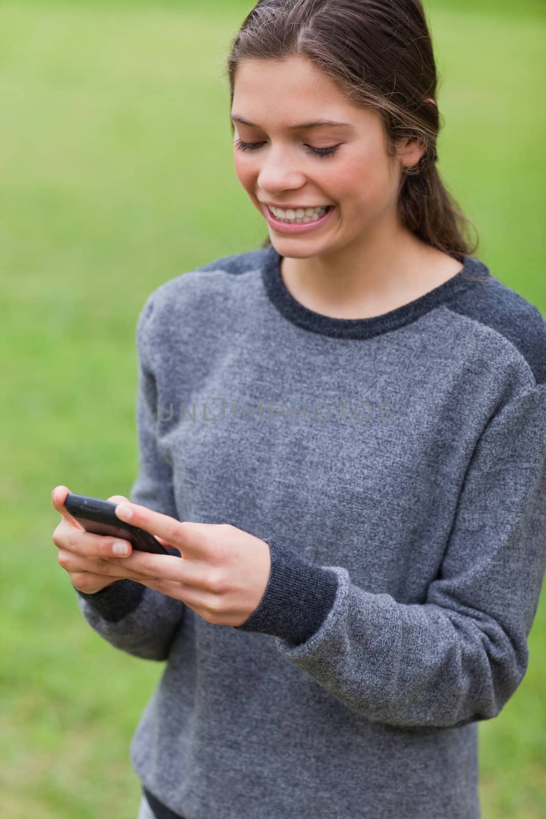 Young girl showing a beaming smile while sending a text by Wavebreakmedia