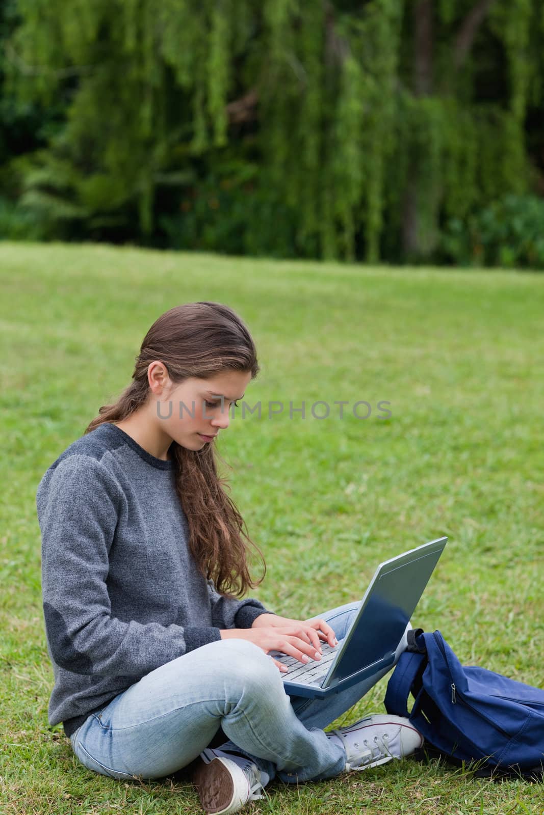 Serious young woman typing on her laptop while sitting cross-leg by Wavebreakmedia