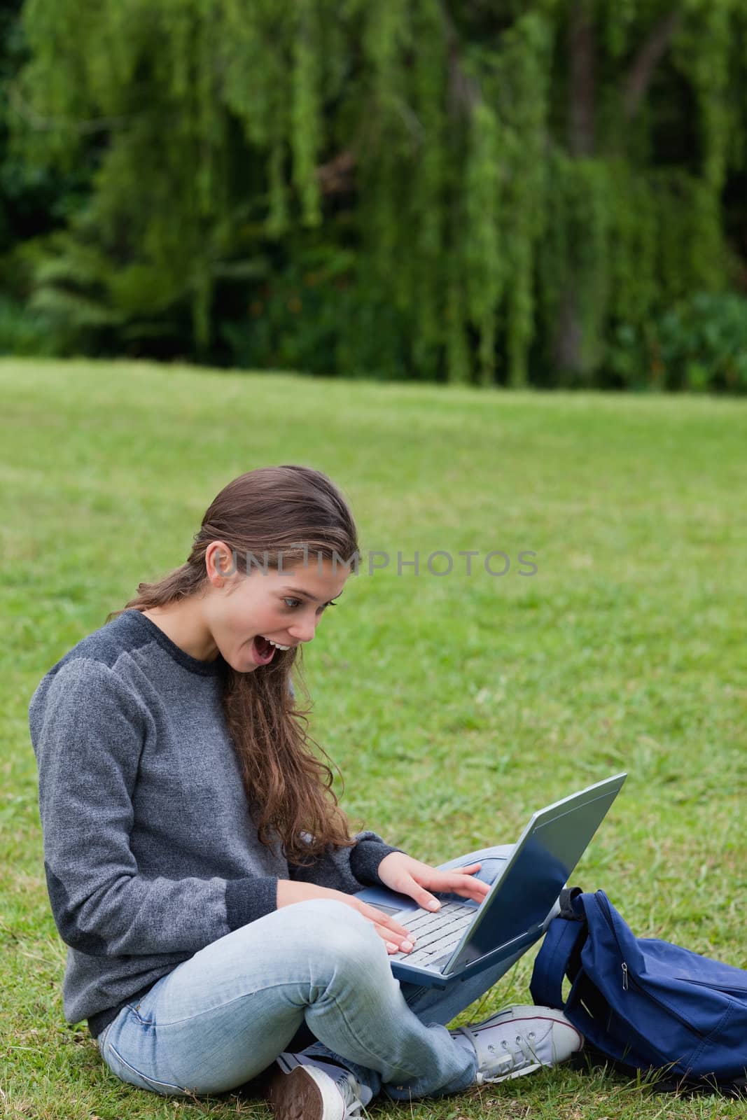 Surprised young girl looking at her laptop while sitting on the  by Wavebreakmedia