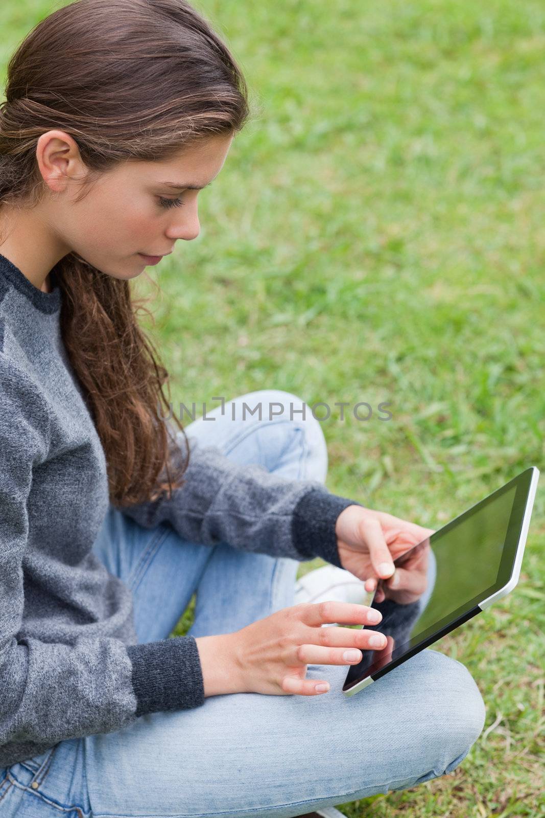 Young smiling girl sitting cross-legged while touching her table by Wavebreakmedia